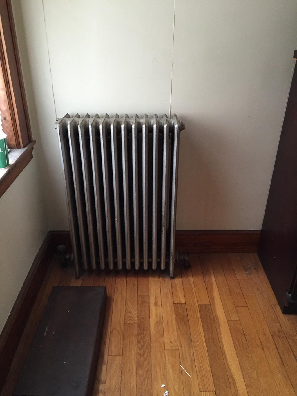 A black radiator is on a wooden floor in a room.