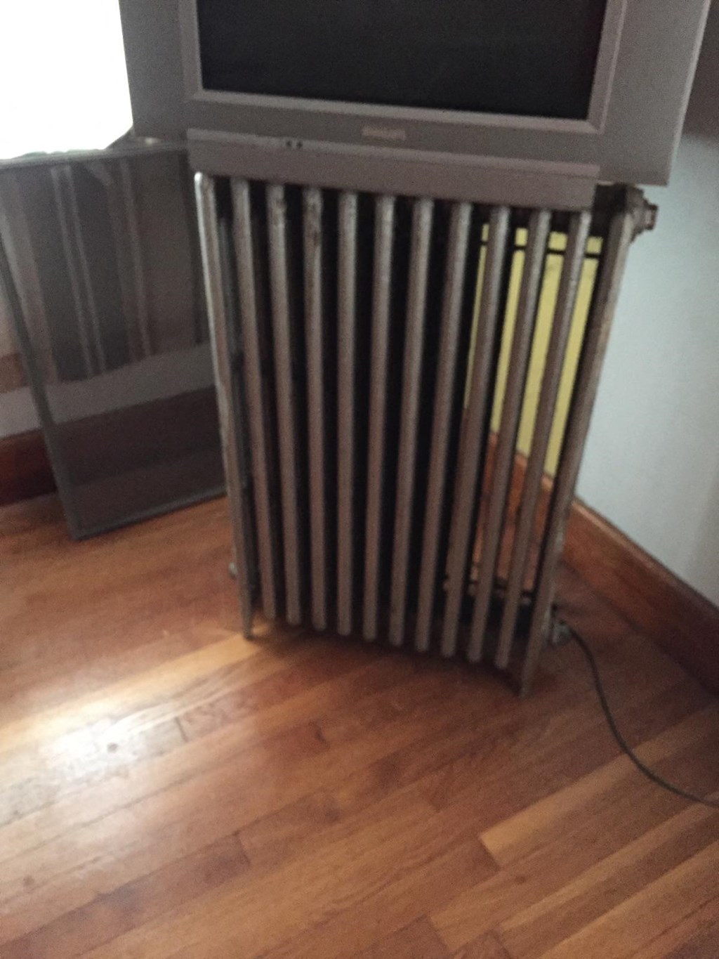 A silver television is mounted on a wooden stand.