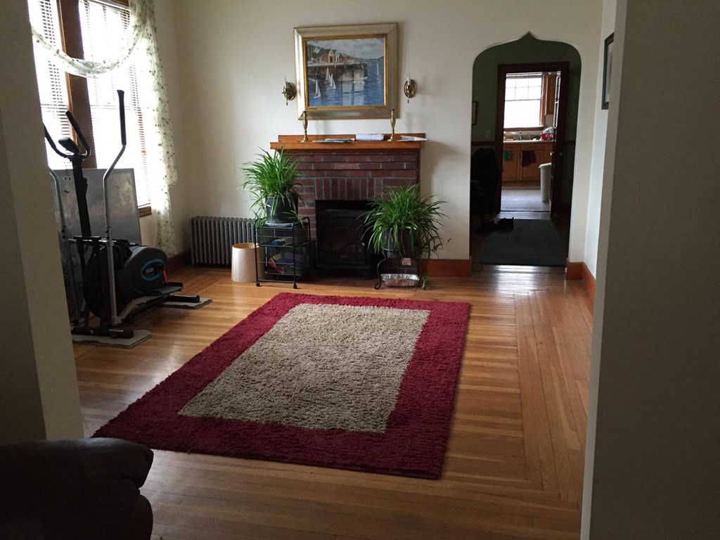 A living room with a fireplace and a rug.