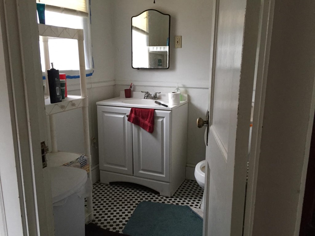 A white bathroom with a black and white floor.
