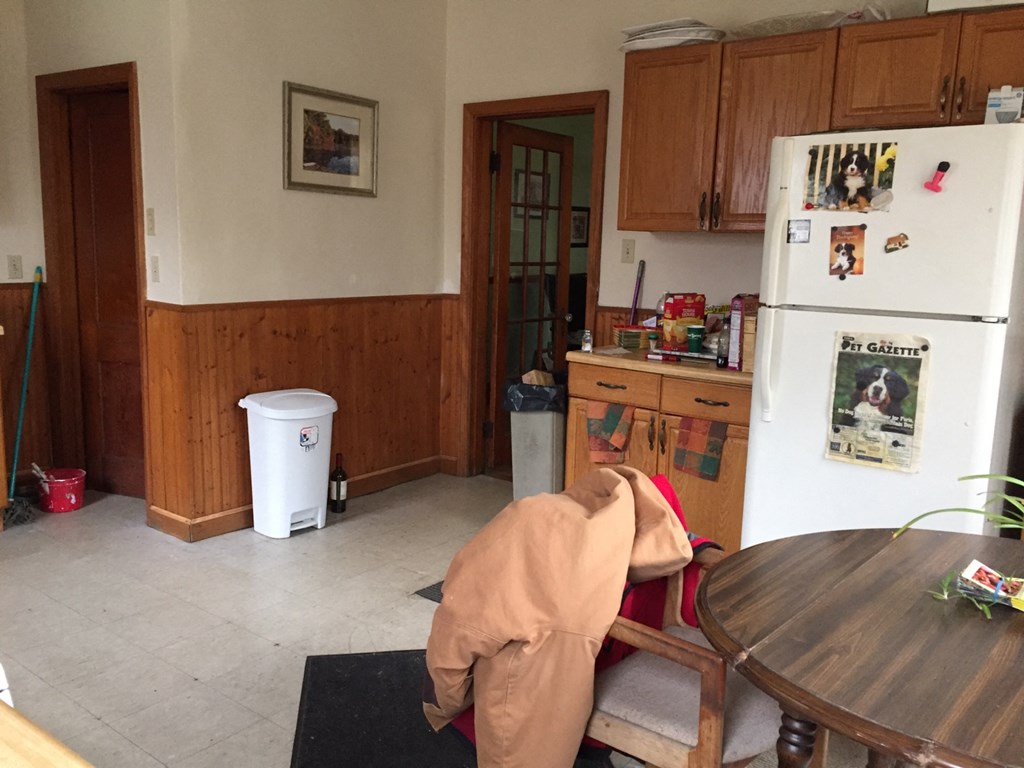 A man in a brown jacket is bending over a black mat in a kitchen.