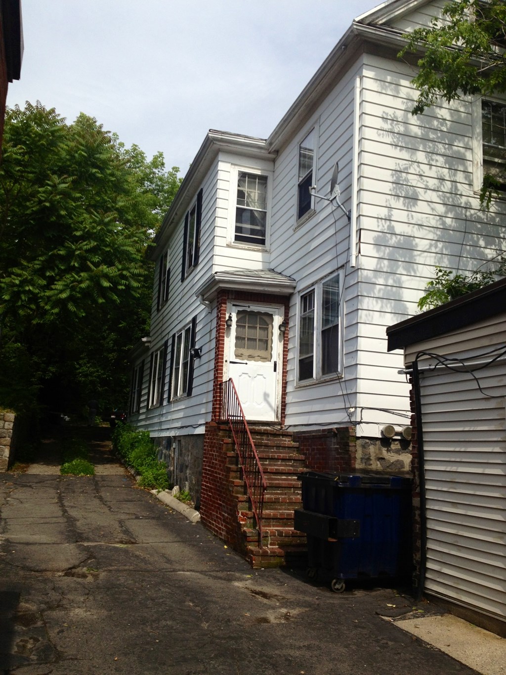 A white house with a blue door and a red staircase.