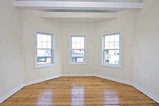 an empty room with a wooden floor and three windows