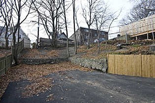 a stone retaining wall and a wooden fence in front of a house
