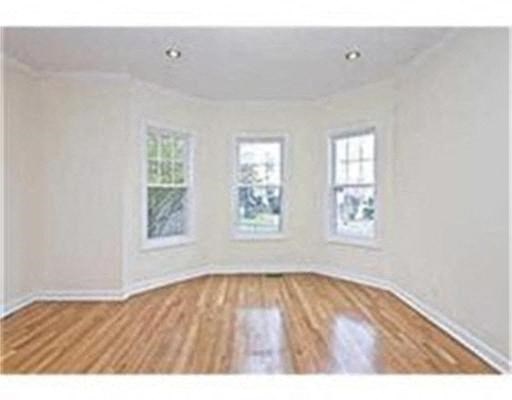 a large empty living room with a wooden floor and three windows