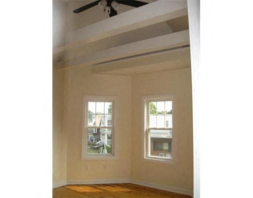 an empty room with a ceiling fan and two windows