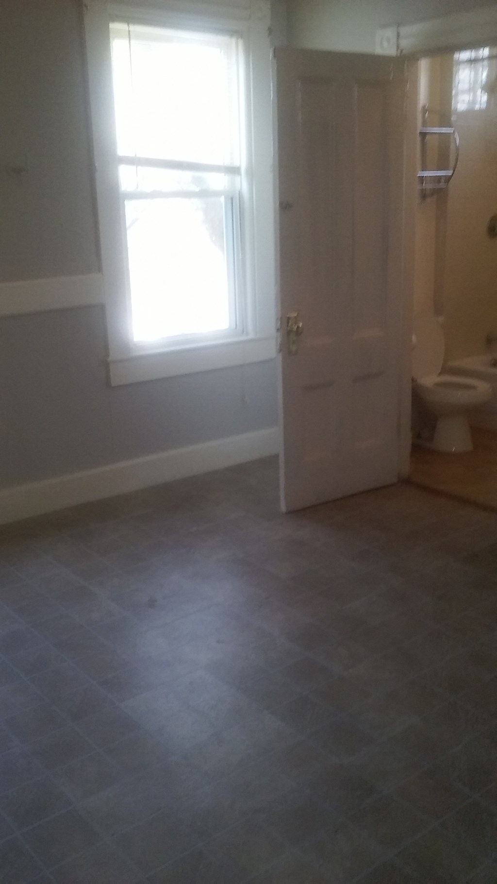 an empty bathroom with a toilet and a window
