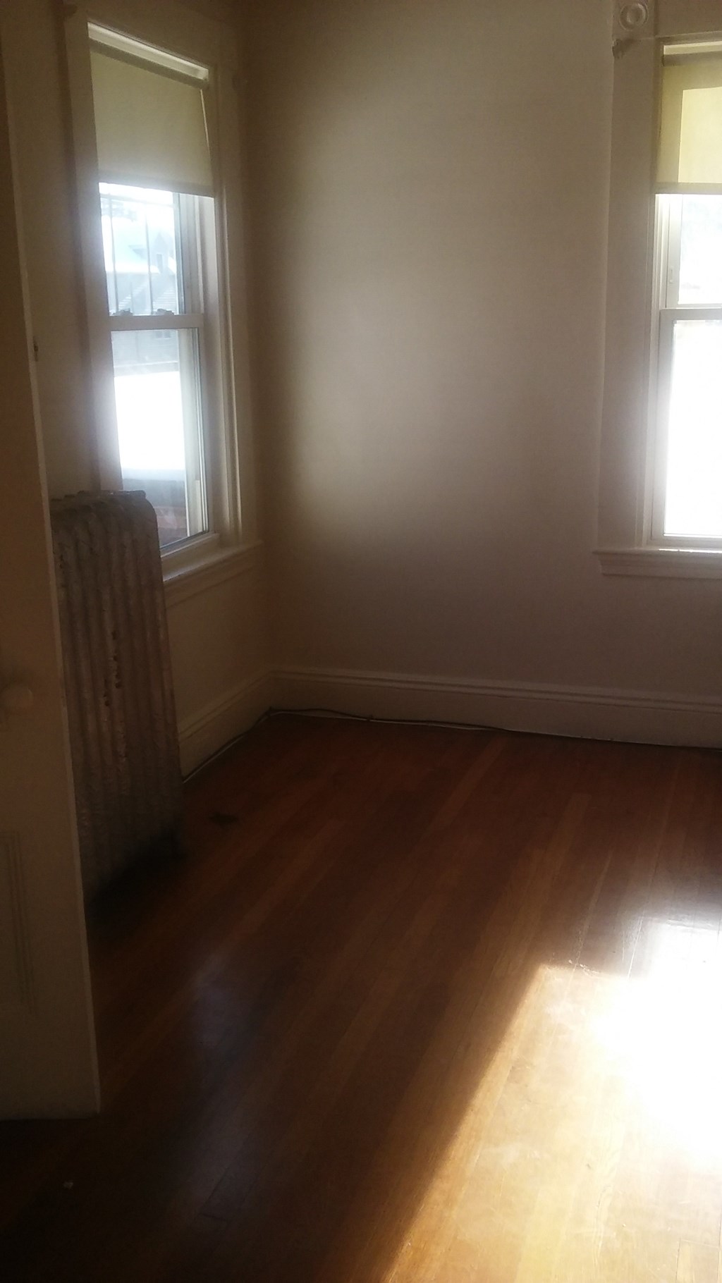 the living room of a house with wooden floors and two windows