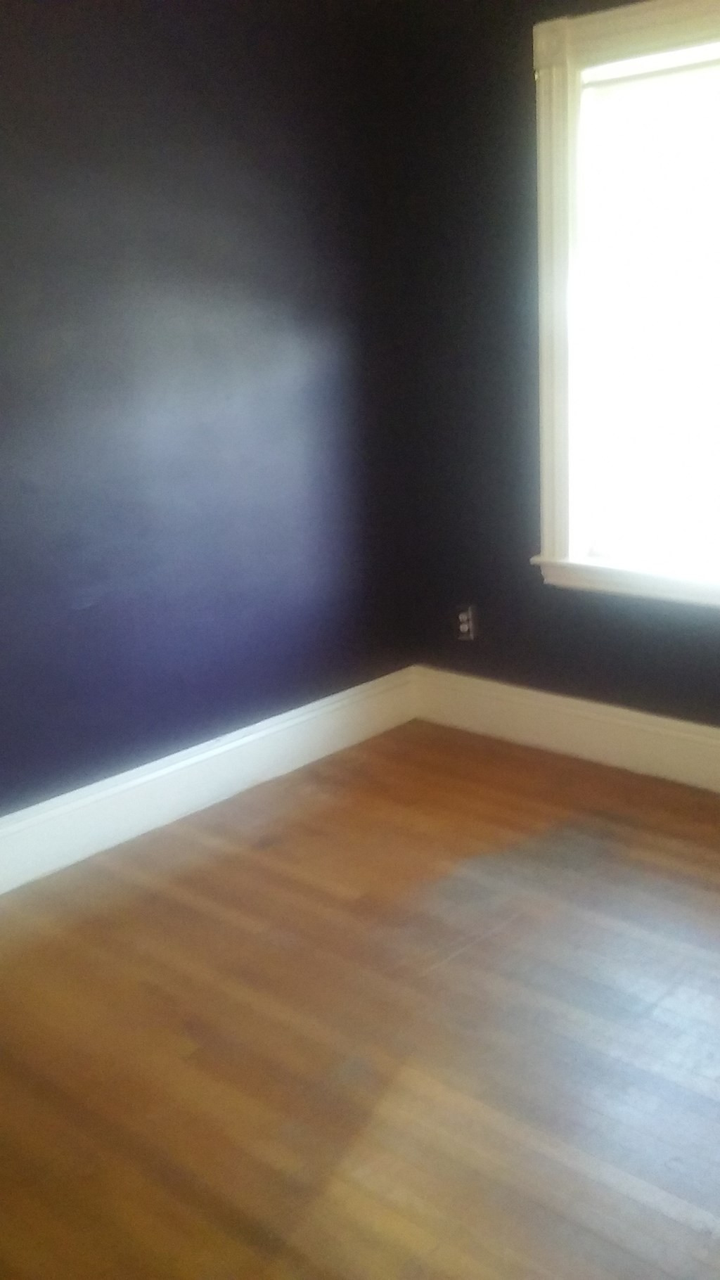 an empty room with black walls and wooden floors