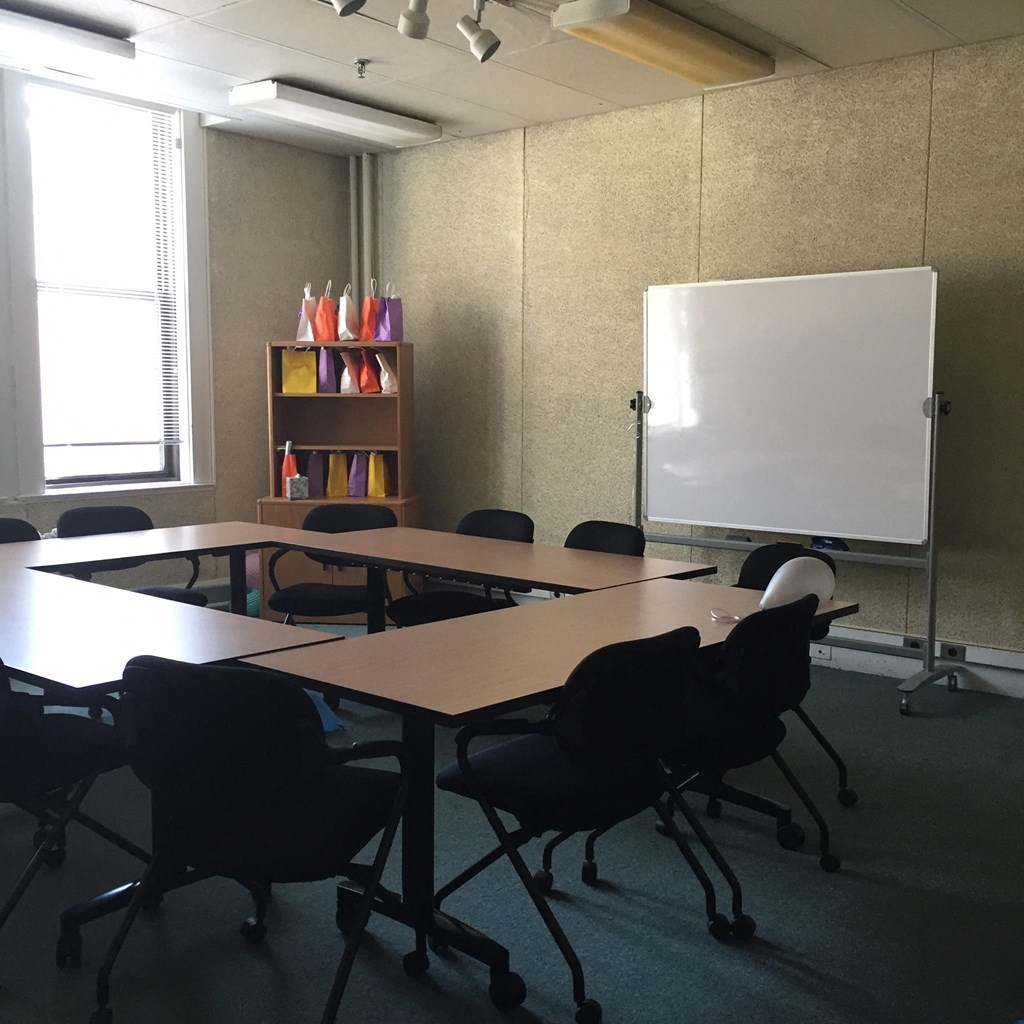 a conference room with tables and chairs and a white board
