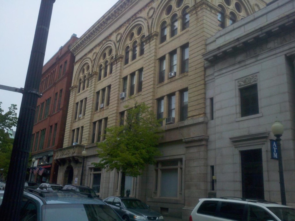 a building on a city street with cars and a tree