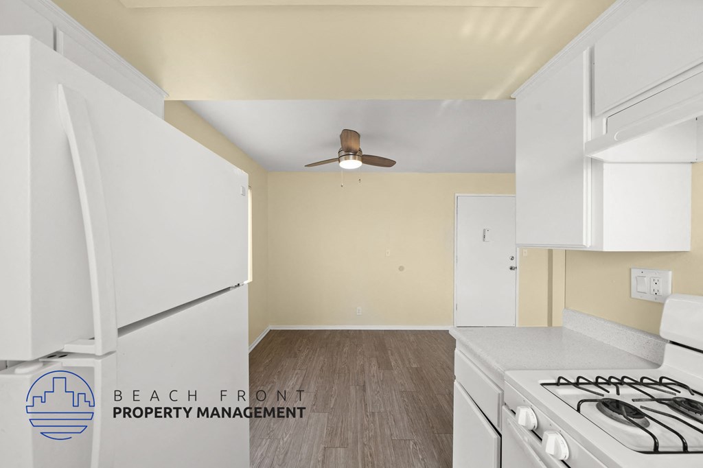 A kitchen with white appliances and a logo for Beach Front Property Management.