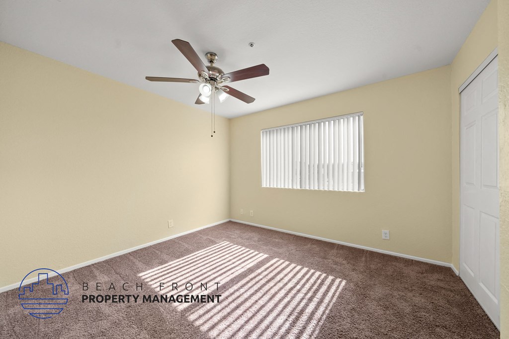 A room with a ceiling fan and a window with blinds.