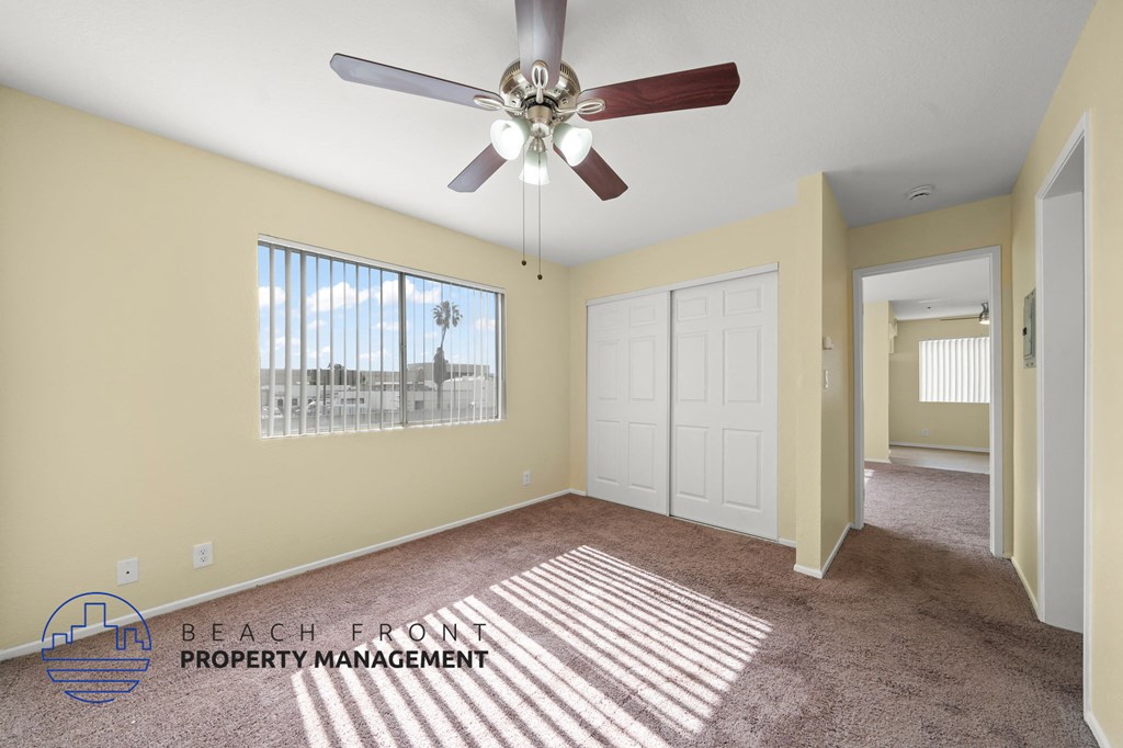 A room with a ceiling fan and a window with blinds.