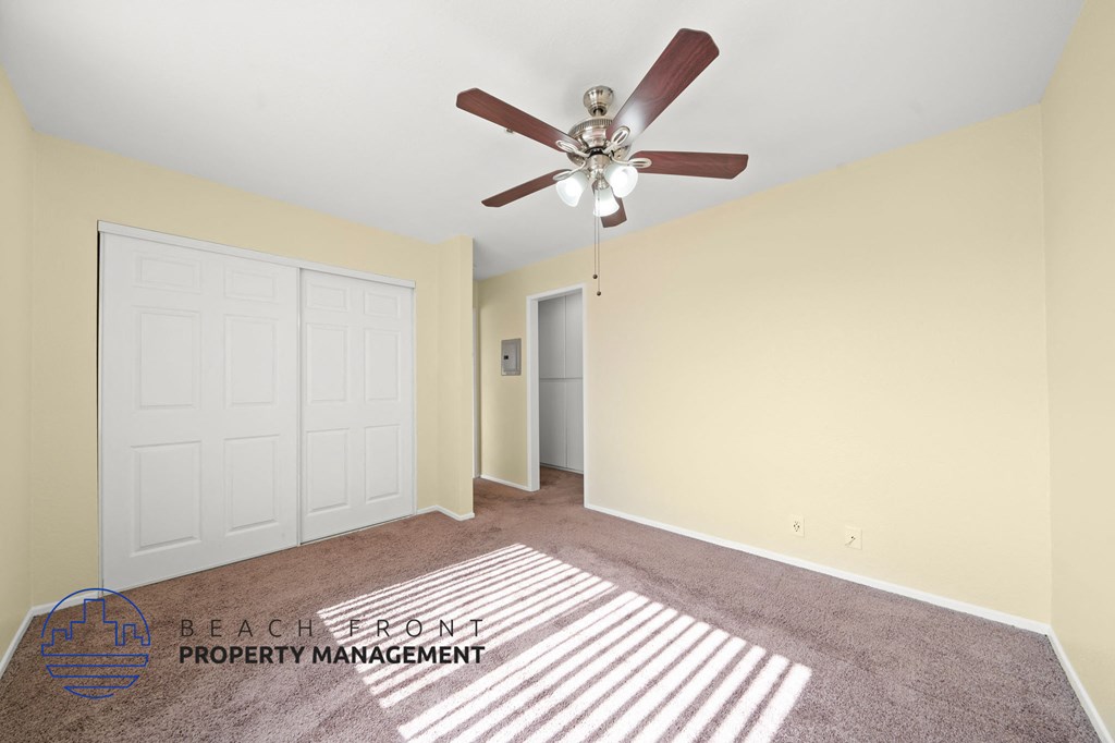 A room with a ceiling fan and a rug on the floor.