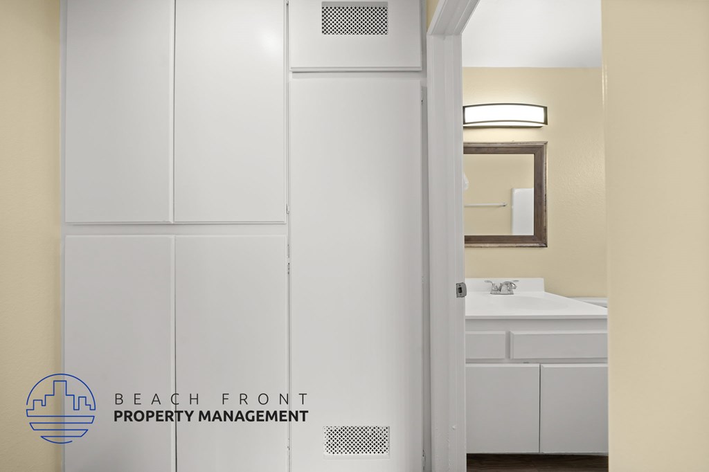 A bathroom with a sink and a mirror is shown with the logo of Beach Front Property Management.