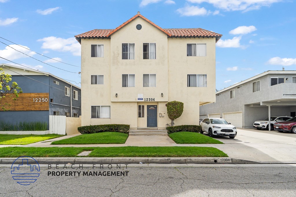 A two-story building with a red tile roof is for sale, managed by Beach Front Property Management.