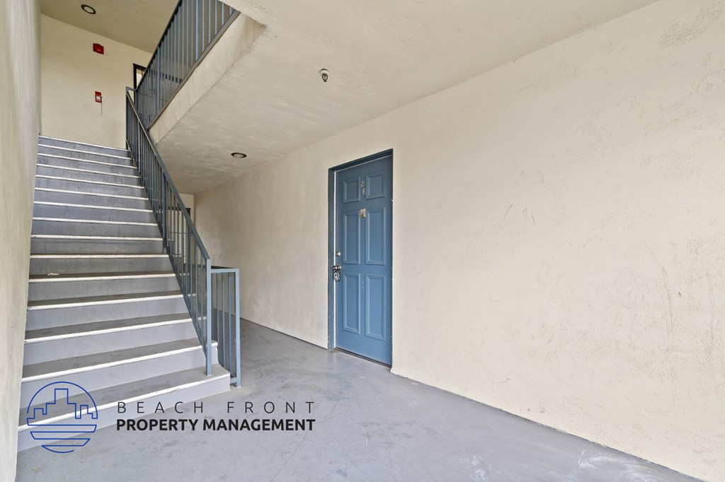 A staircase with a blue door in a white room.