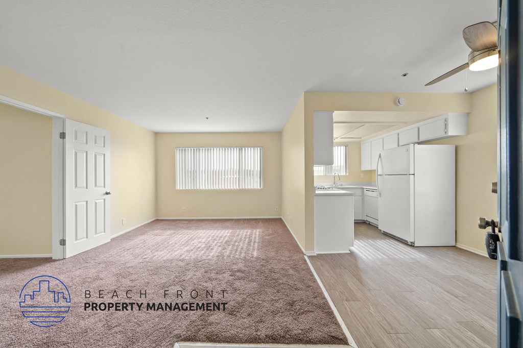 A spacious room with a rug on the floor and a logo for Beach Front Property Management in the corner.