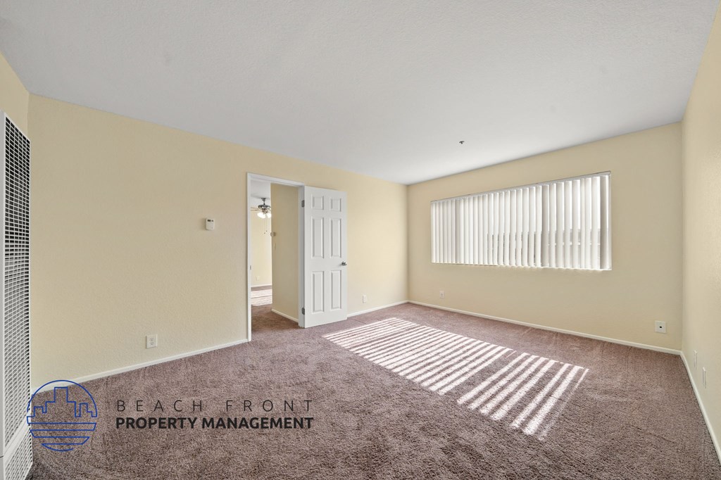A room with a carpeted floor and a window with blinds.