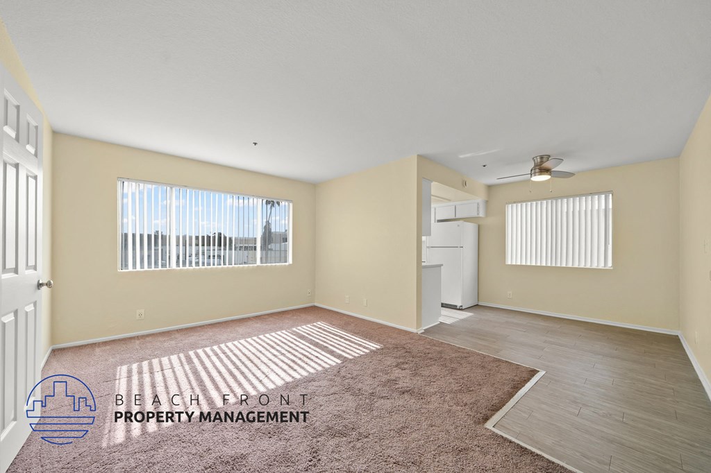 A spacious room with a carpeted floor and a ceiling fan.