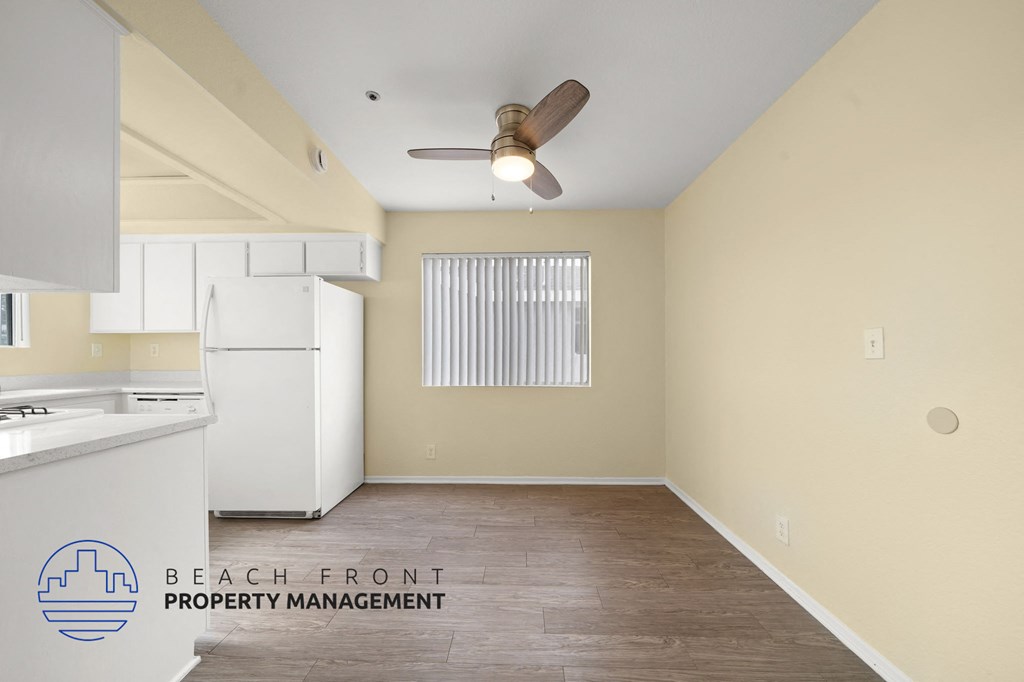 A room with a fan and a window with blinds.