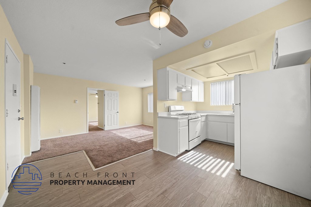 A kitchen area with a refrigerator, sink, and a fan.