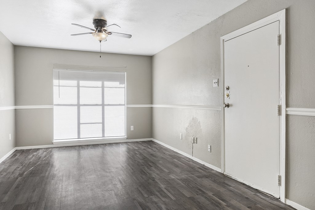 an empty living room with a ceiling fan and a window