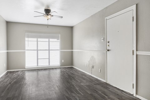 an empty living room with a ceiling fan and a window