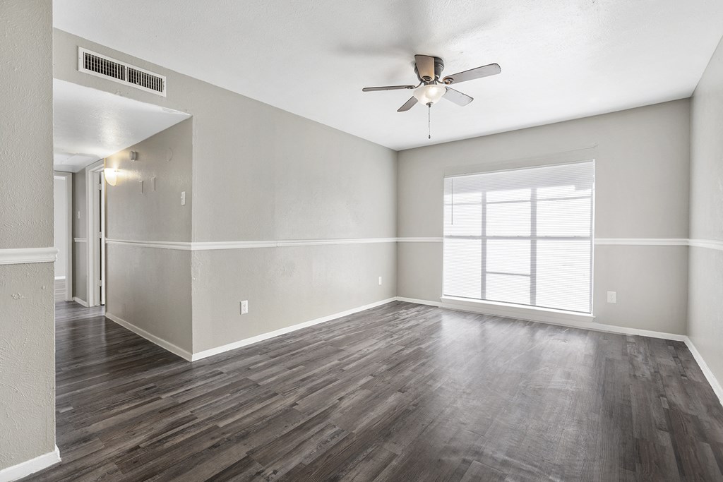 an empty living room with a ceiling fan and a window