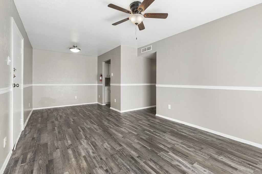 an empty living room with wood floors and a ceiling fan