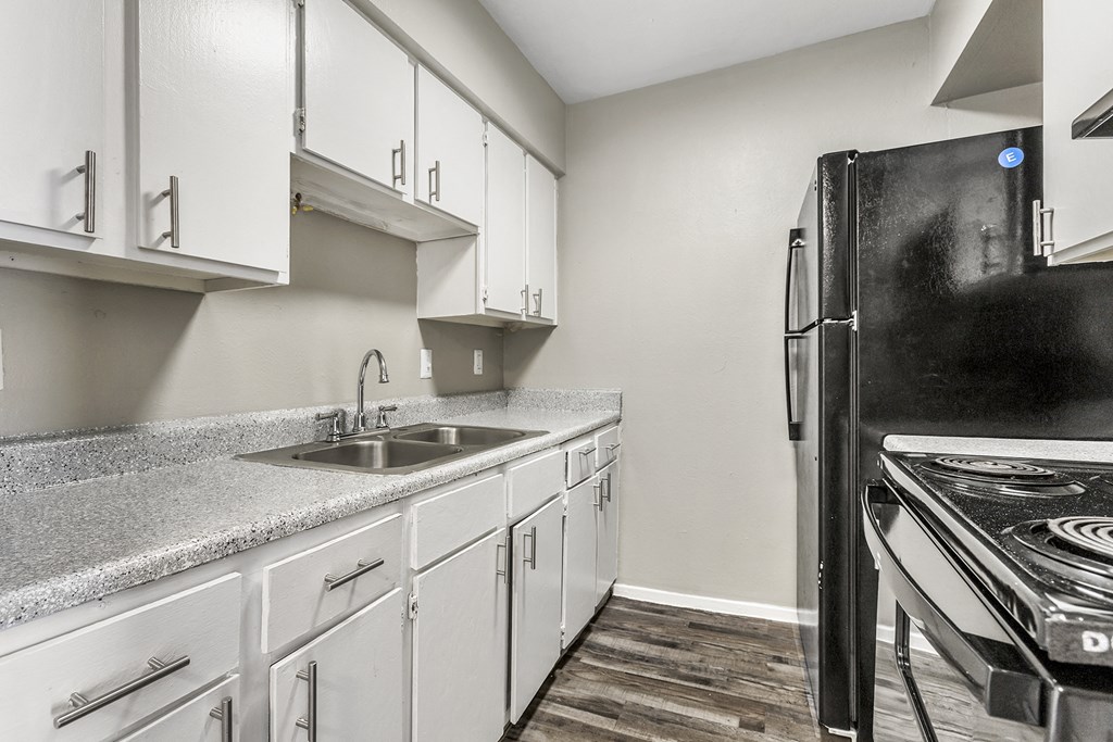an empty kitchen with white cabinets and a black refrigerator