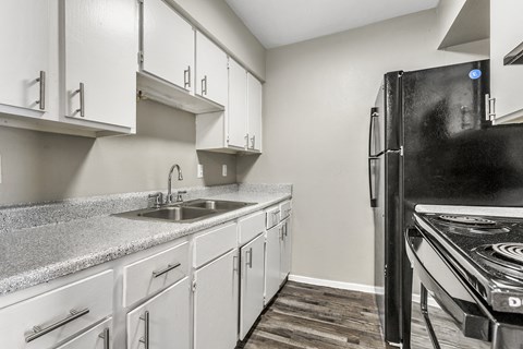 an empty kitchen with white cabinets and a black refrigerator