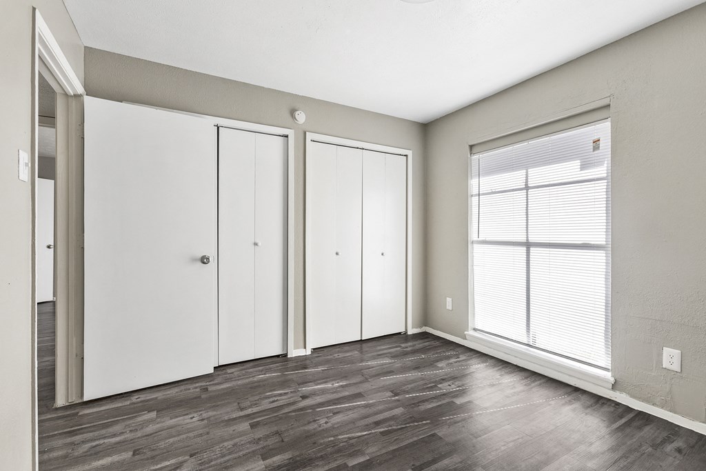 the living room of an apartment with white walls and wood floors
