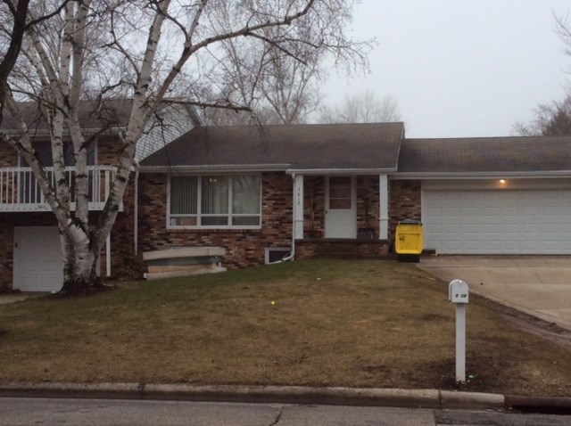 the front of a brick house with a lawn and a tree