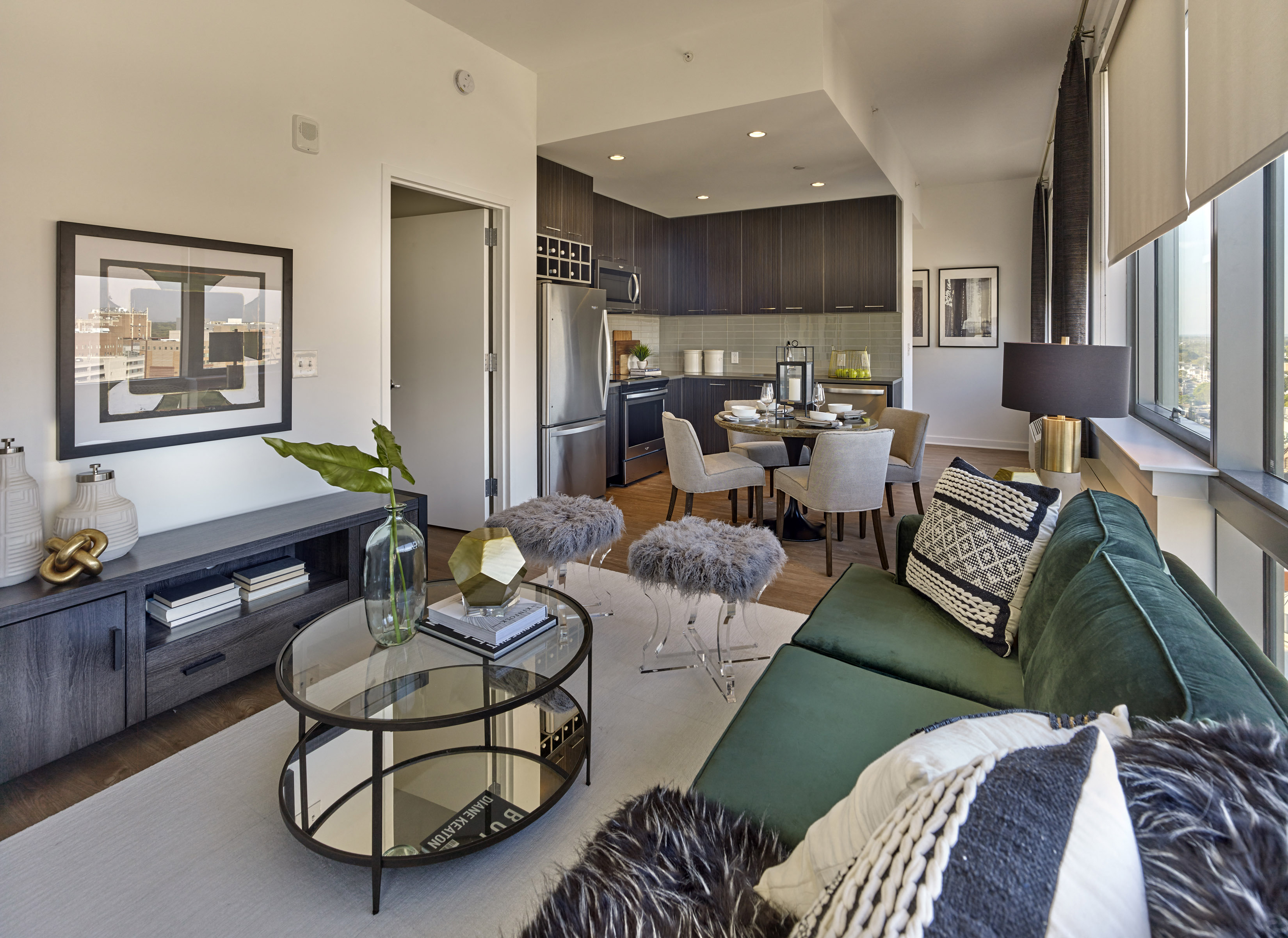 A modern living room with a glass coffee table and a green sofa.