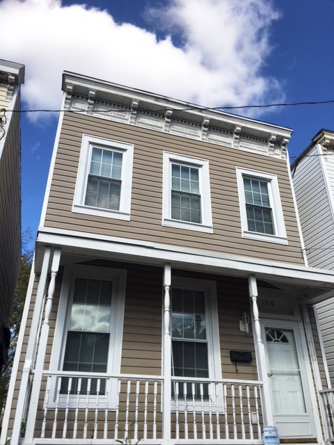 a brown house with a white porch and a blue sky