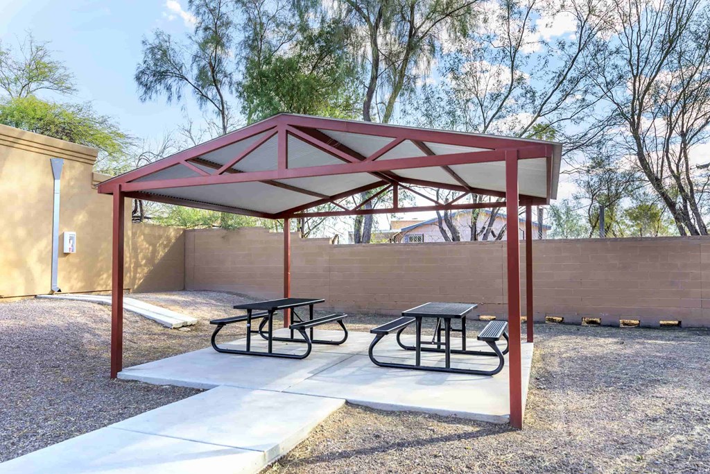 A picnic area with a red and white canopy and two tables.