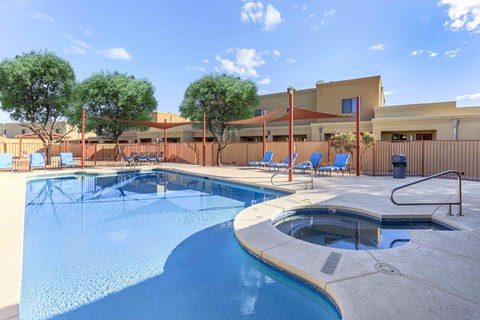 A swimming pool with a hot tub and lounge chairs.