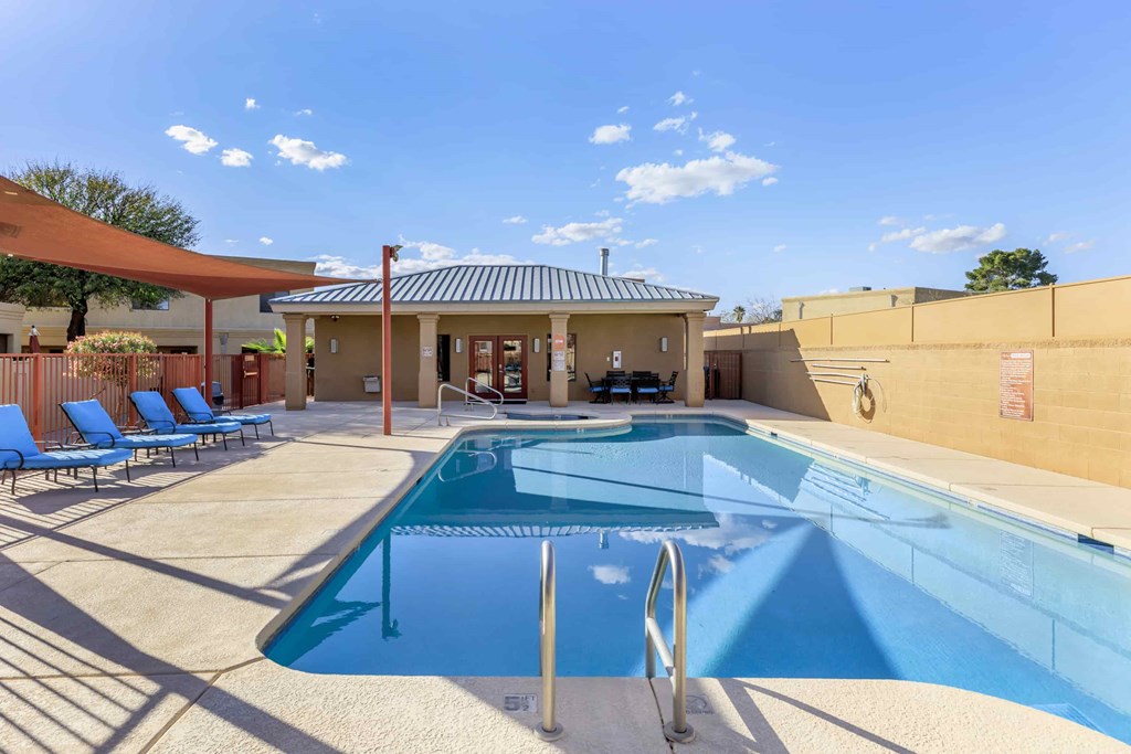 A pool with a diving board and a small building behind it.