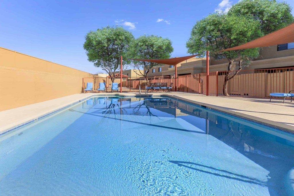 A swimming pool with a sun lounger and umbrella.