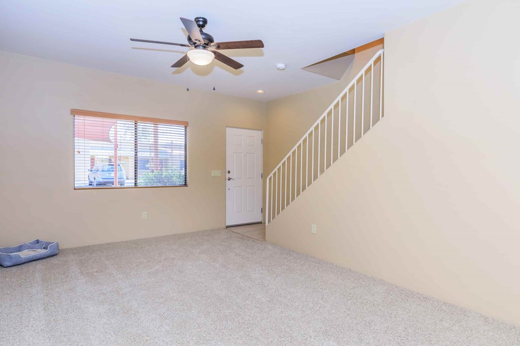 A room with a ceiling fan and a staircase.