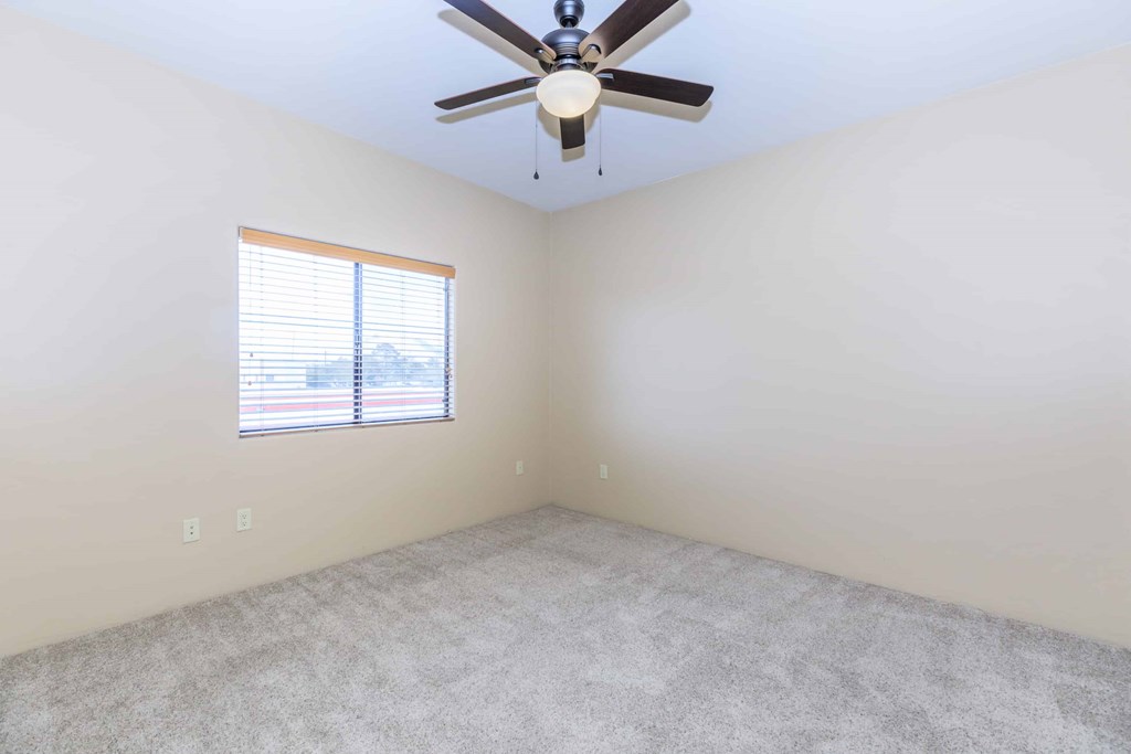 A room with a ceiling fan and a window with blinds.