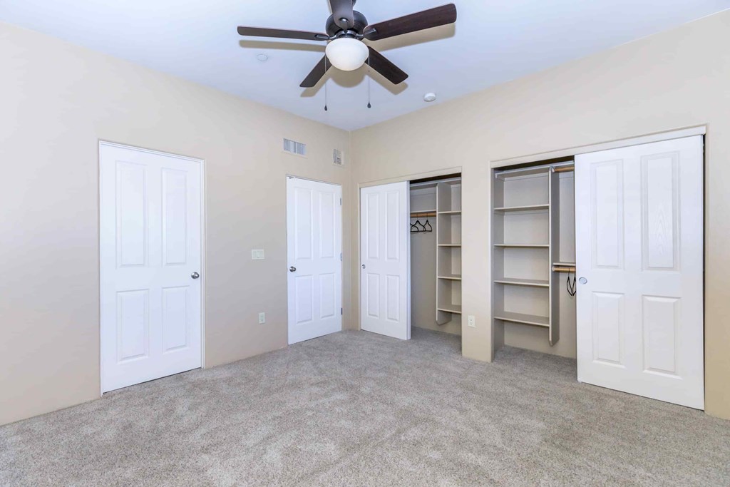 A room with a ceiling fan and four doors.