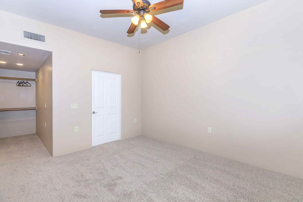 A room with a ceiling fan and a door.