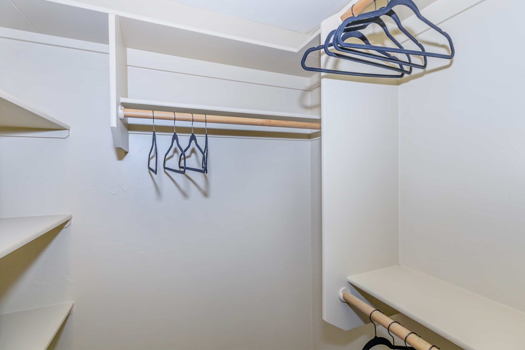 A white closet with a white shelf and a white bench.