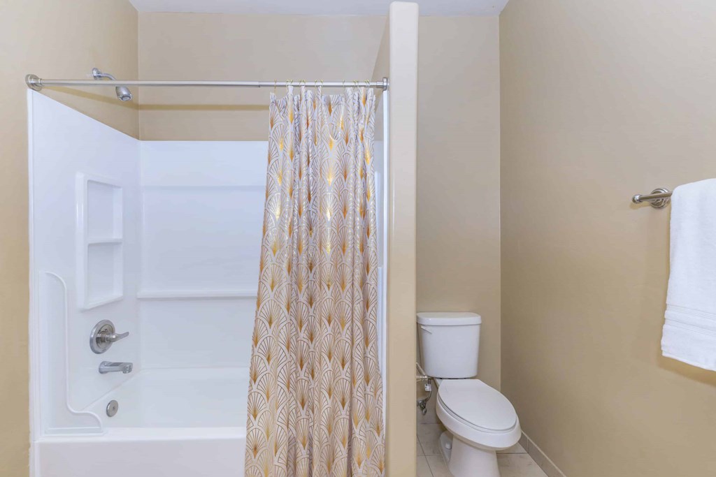 A white toilet sits next to a bathtub with a shower curtain.