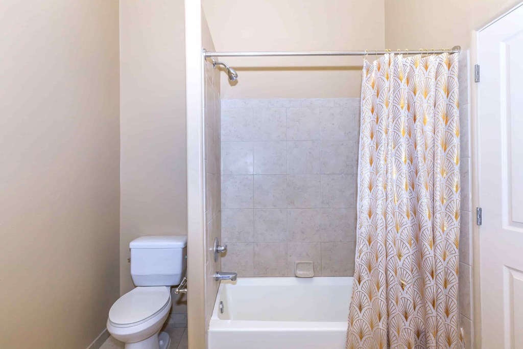 A white toilet sits next to a bathtub in a bathroom.