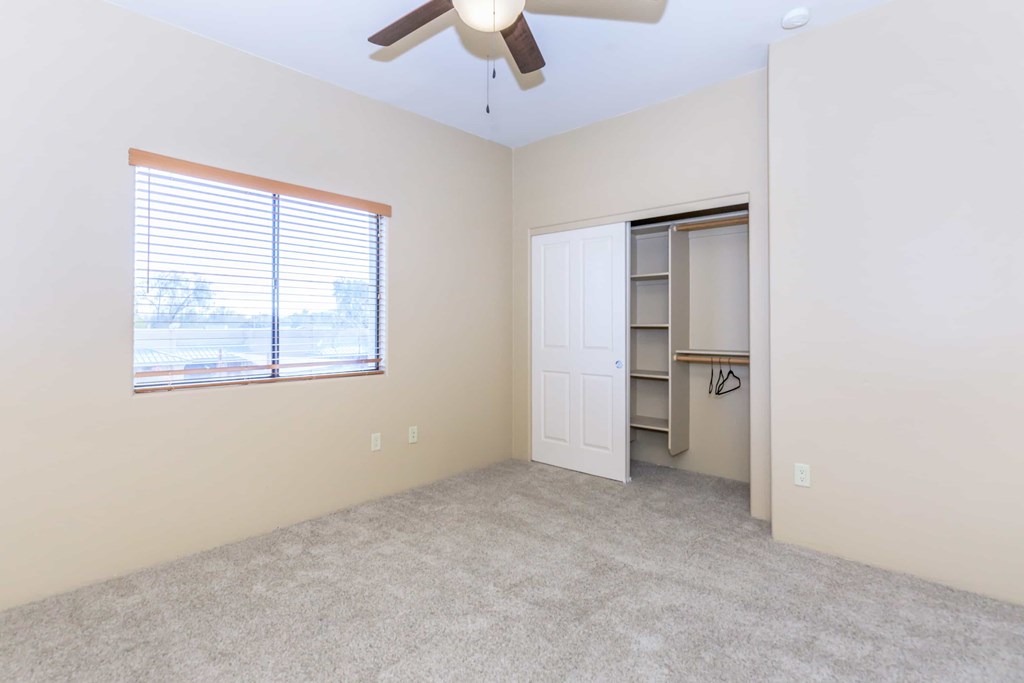 A room with a ceiling fan and a window with blinds.