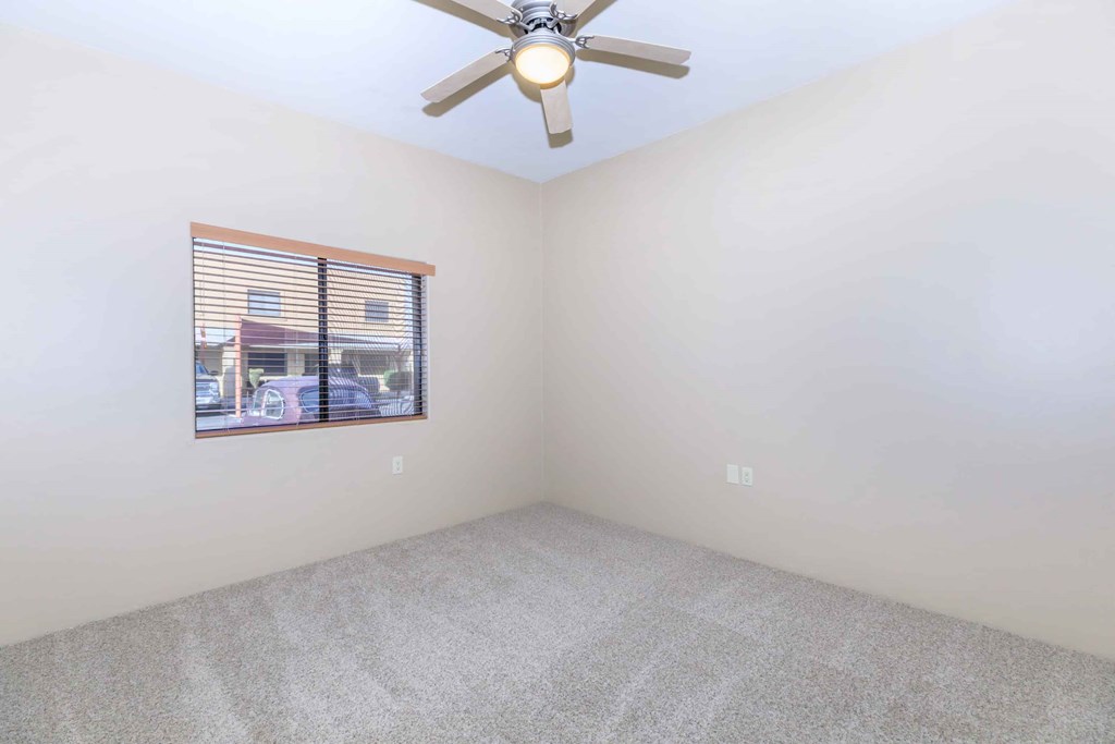 A room with a ceiling fan and a window with blinds.